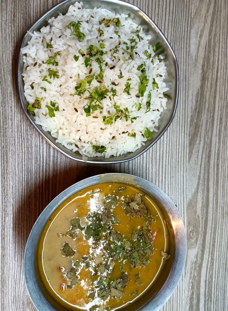 Rice and dal in steel bowls, the base of a Sunita Caterers thali