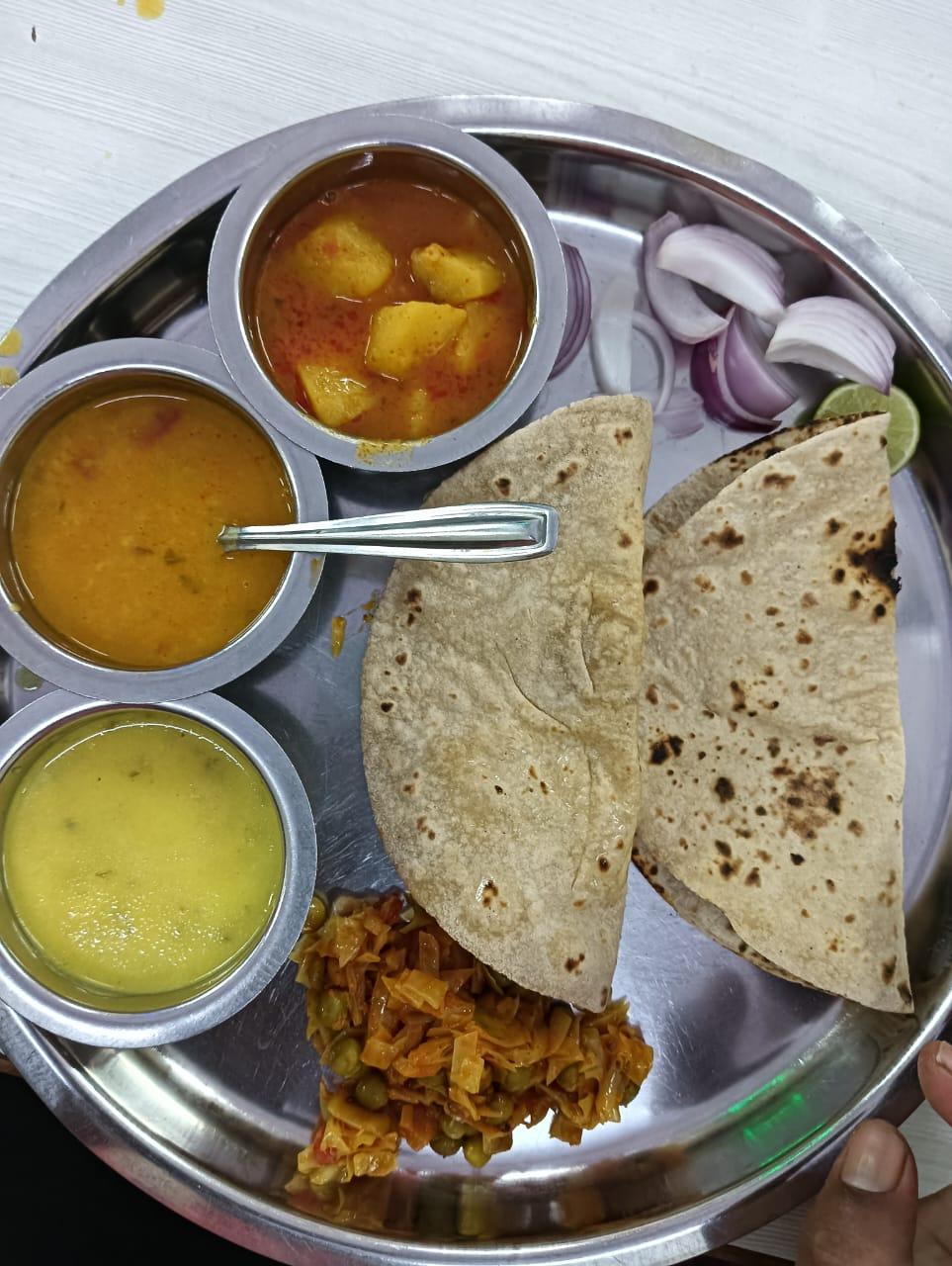 A full steel-plate thali from Sunita Caterers with sabzi, dal, roti and salad